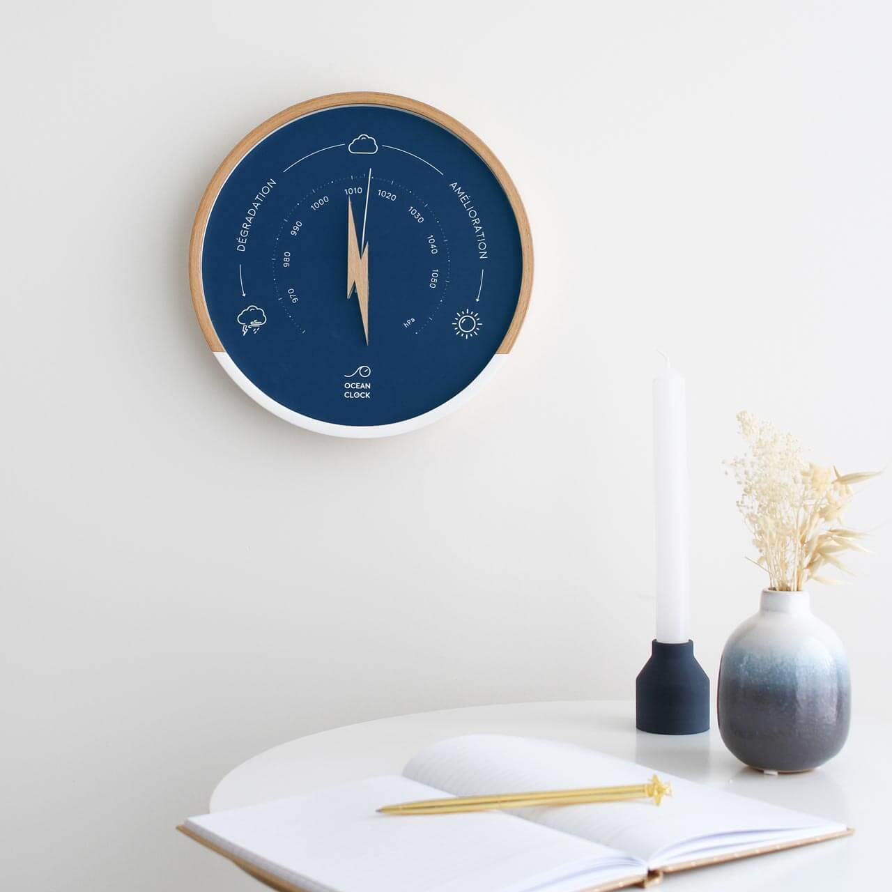 navy blue and wood barometer on a wall next to a table with a notebook